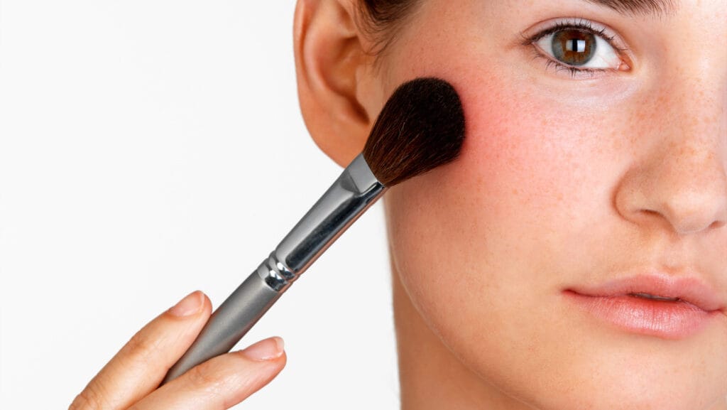 אישה שמה סומק עם מברשת