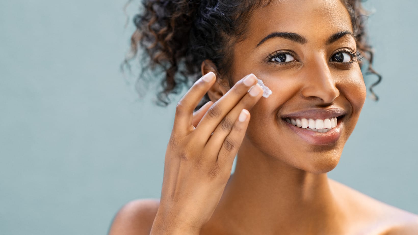 אישה מורחת קרם לחות לעור יבש על הלחי