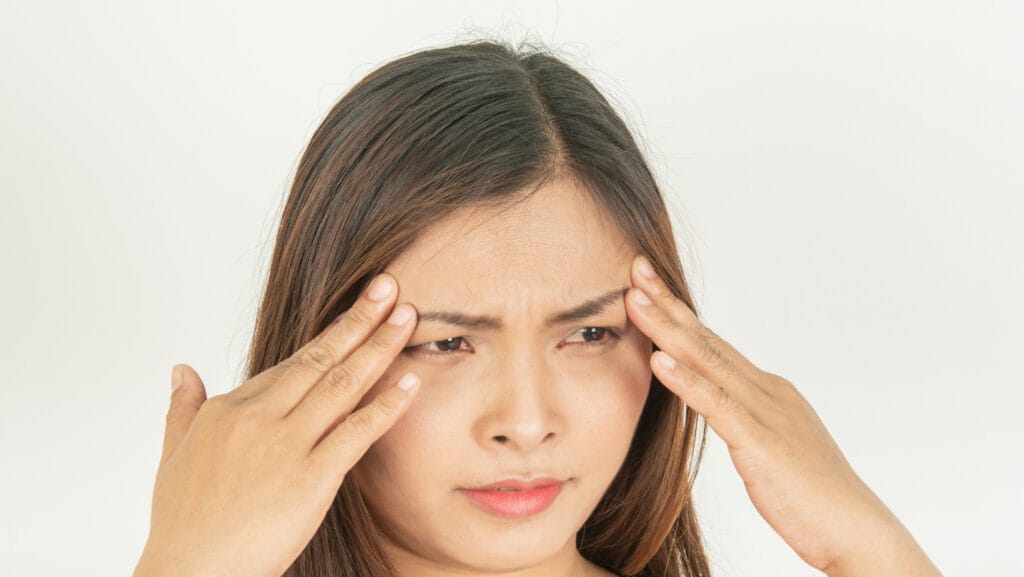 אישה נוגעת בגבות שלה בזמן שהיא עושה קמטי הבעה במצח