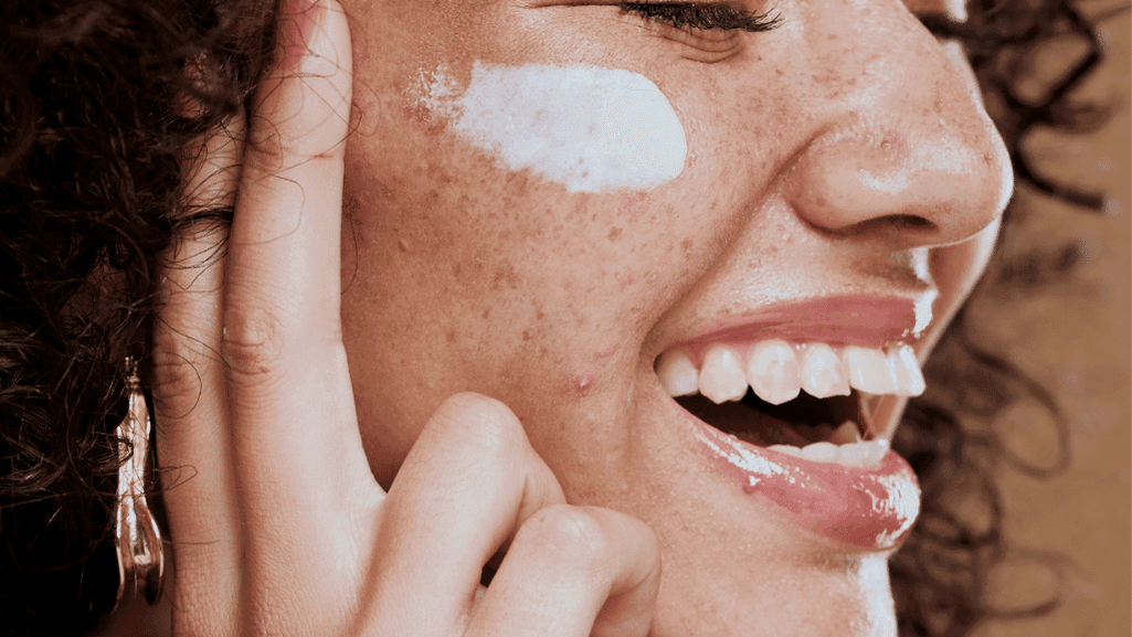 אישה מנומשת שמה קרם לחות על העור