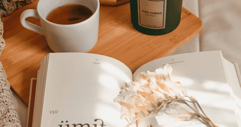 פרחים מיובשים מונחים על ספר עם כוס תה ברקע על מגש