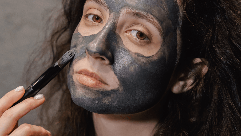אישה מורחת על עצמה מסכת בוץ על הפנים